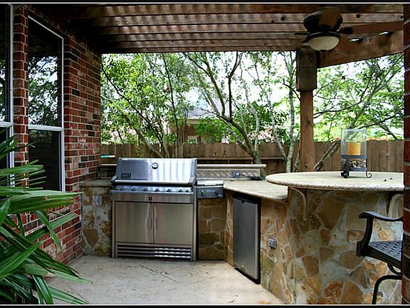 The outdoor kitchen has stainless steel appliances ~ a built in grill and refrigerator...located jus