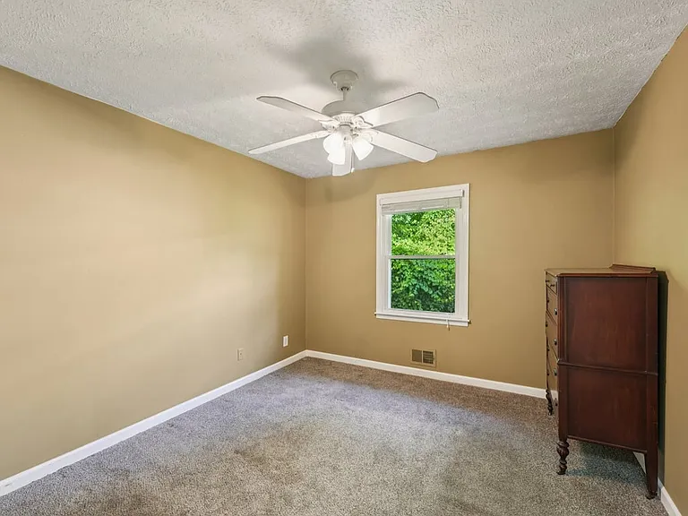 A serene bedroom wrapped in warm golden tones, soft carpeting, and peaceful greenery outside the window, creating a restful retreat with gentle storybook charm.
