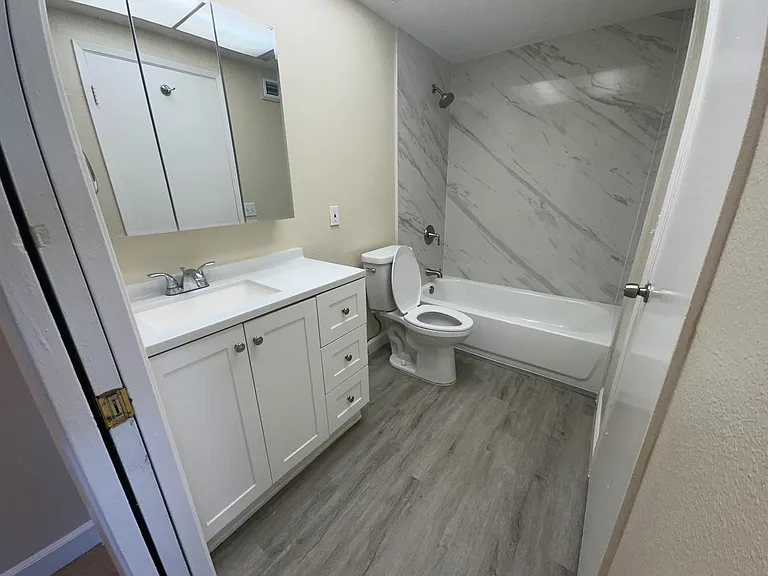 Remodeled bathroom with modern marble slab and new vanity/toilet/medicine cabinet
