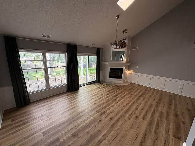 Living room with new flooring/paint, and gas fireplace.