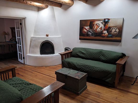 Living room with working kiva fireplace, original Native American painting and solar tube lighting. (Shows seating covered by slipcovers for guests with pets)