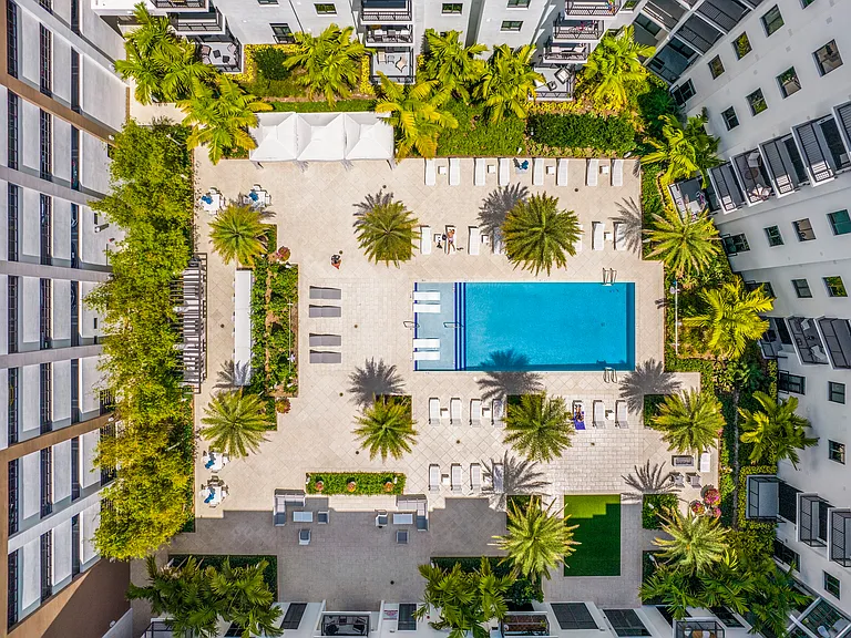 Resort-style pool deck surrounded by lush landscaping and sun-soaked spaces.
