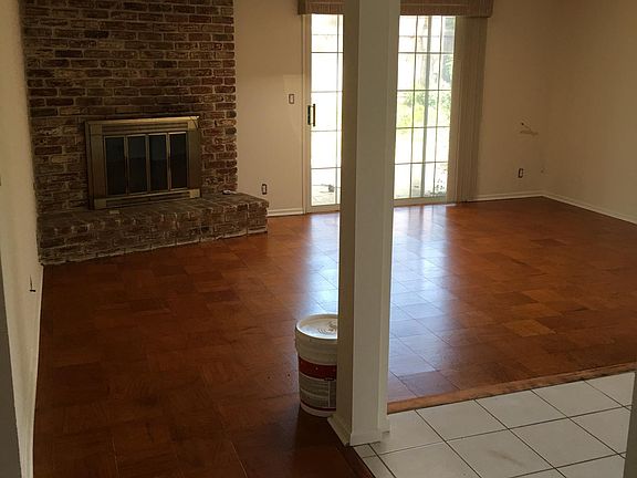 Large living room features a brick fireplace, large skylight, hardwood floor, and sliding patio door.