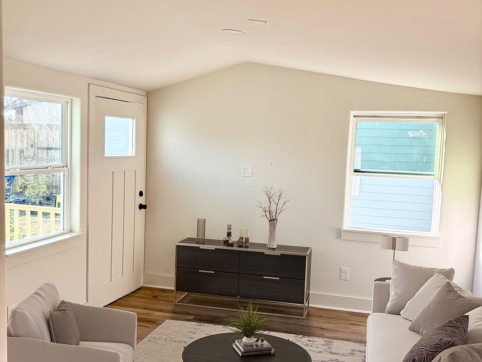 Stand-alone living room with vaulted ceiling and three windows. LVT floor throughout.