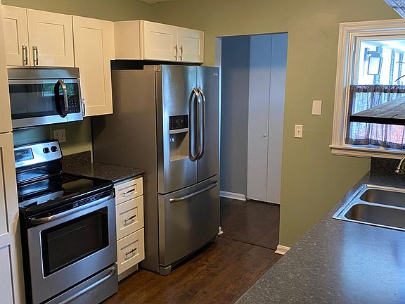 Kitchen view #2 shows remaining appliances and custom cabinetry with functional pull-outs. Coat closet in the back by front door also seen here.