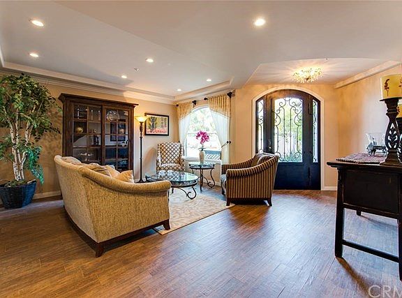 The custom wrought iron and glass door opens into the Living Room with coffered ceiling.  Most floors feature a light colored "wood like" porcelain tile.
