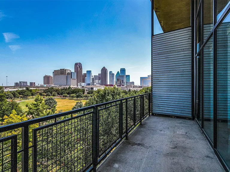 Private balcony with concrete flooring, black metal grid railing, and a corrugated metal wall