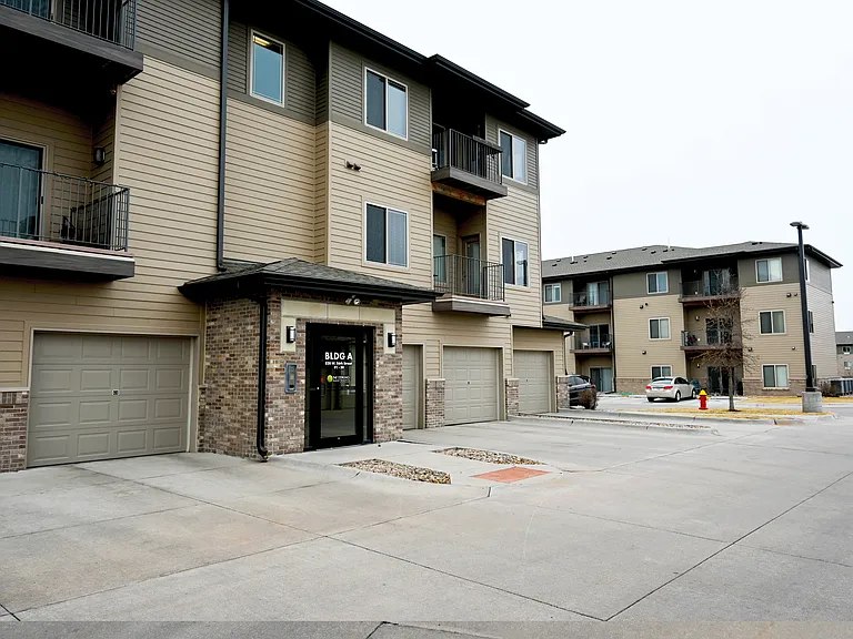 Apartment complex with a parking lot in front.