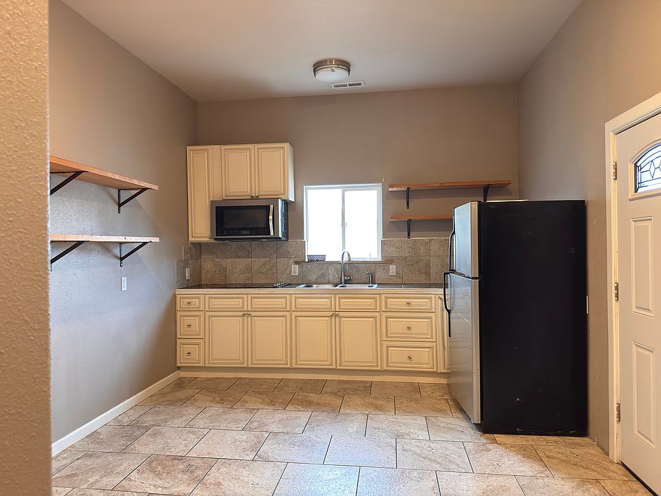 Main entry door and kitchen space, with microwave, stove, and refrigerator
