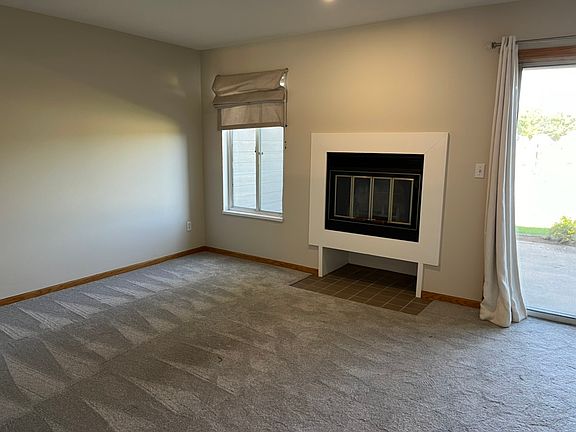 Living room with working fireplace, pass through window to the kitchen, and a sliding glass door to the patio.