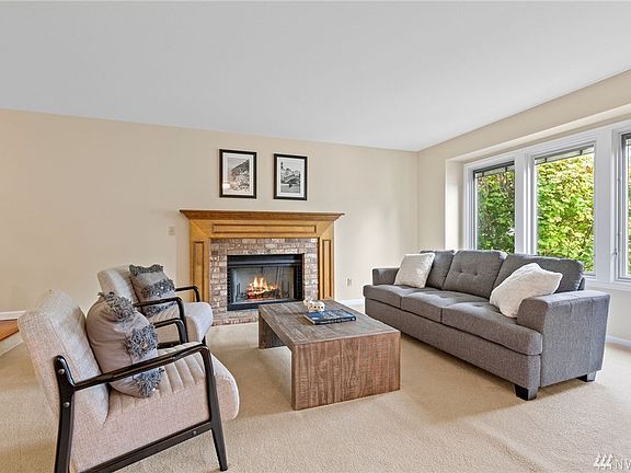 Open and bright living room with gas fireplace. Upgraded double pane windows feature blind-in-glass. 