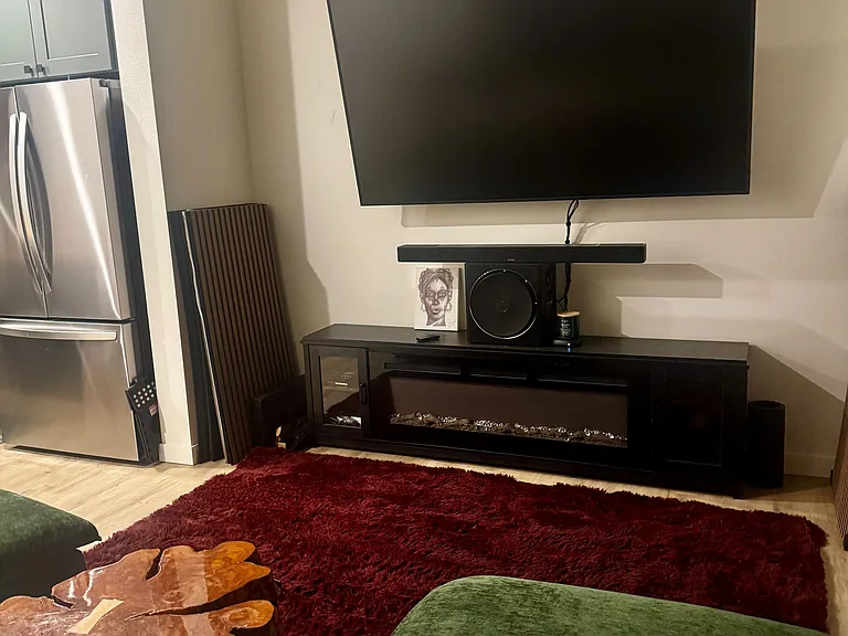 Inviting living area with wall-mounted TV, media console, and open layout connecting to the kitchen for easy entertaining.