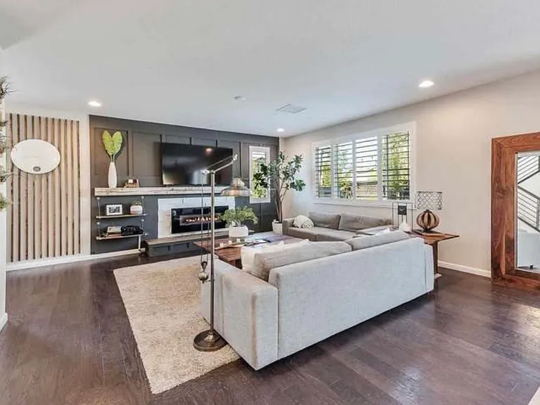 Living room with custom entertainment center. Plantation shutters throughout entire home with hardwood floors.