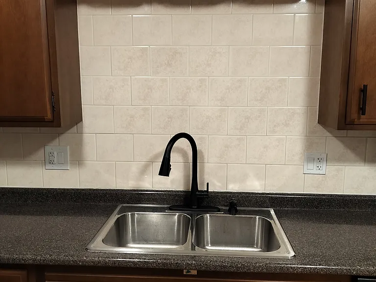 Ceramic backsplash surrounds countertop and sink.