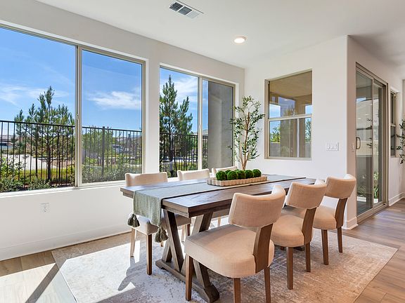 A modern and spacious dining room with large windows overlooking a scenic outdoor landscape featurin