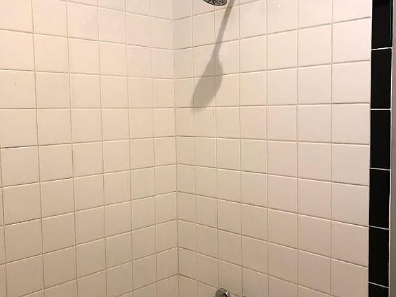 New shower head and faucet, tiled walls.