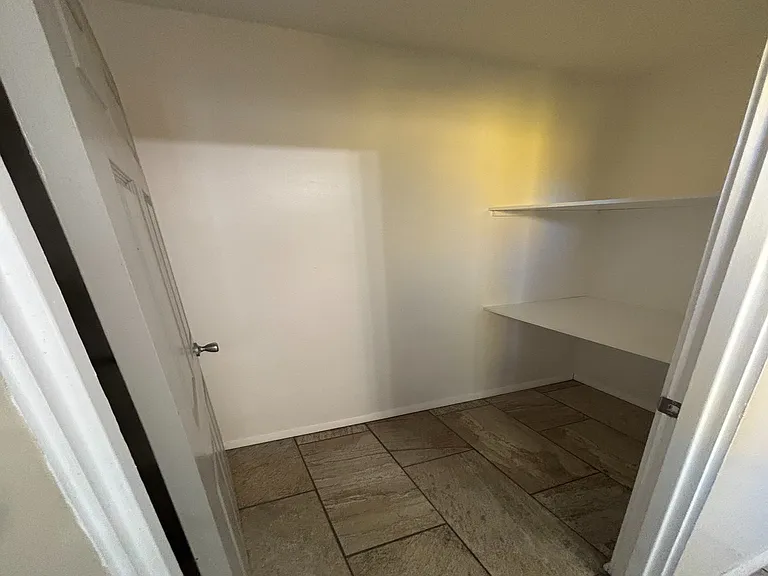 Inviting walk-in closet featuring modern tile flooring and built-in shelving, offering ample storage space.
