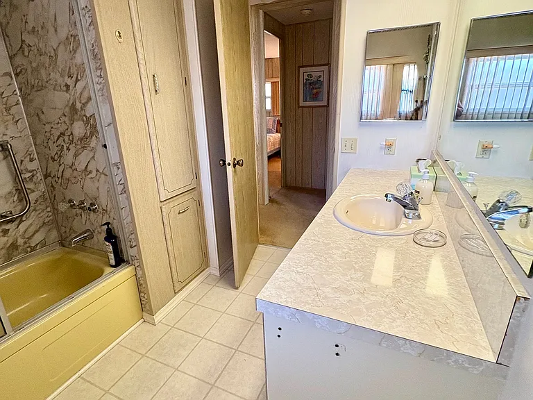 Full hallway bathroom with accessibility bar in bathtub
