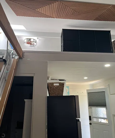 Fan with lights and an outlet on wall in loft along with skylight.
