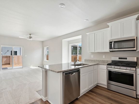 The kitchen has stainless steel appliances and plank flooring.