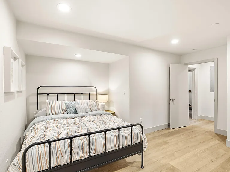 Well-sized bedroom with a full bed setup, recessed lighting, and durable wood-look flooring with easy access to the hall.