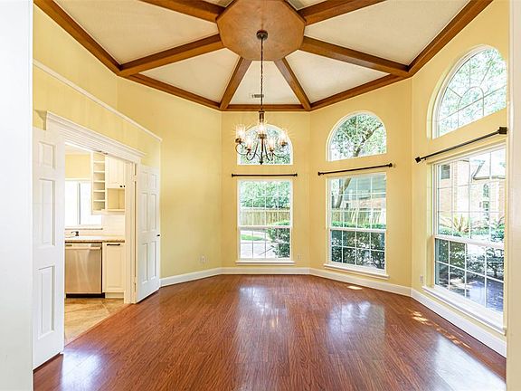 Welcome to one of the most striking dining rooms in Hunterwood Forest! The high ceiling with a wagon wheel design has with an octagonal center with a gorgeous metal and glass chandelier. Huge beans radiate from the wooden center to every corner of th