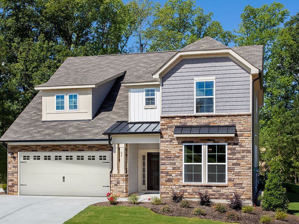 Single family home featuring light color stone watertable, front porch, and a white front two-car ga