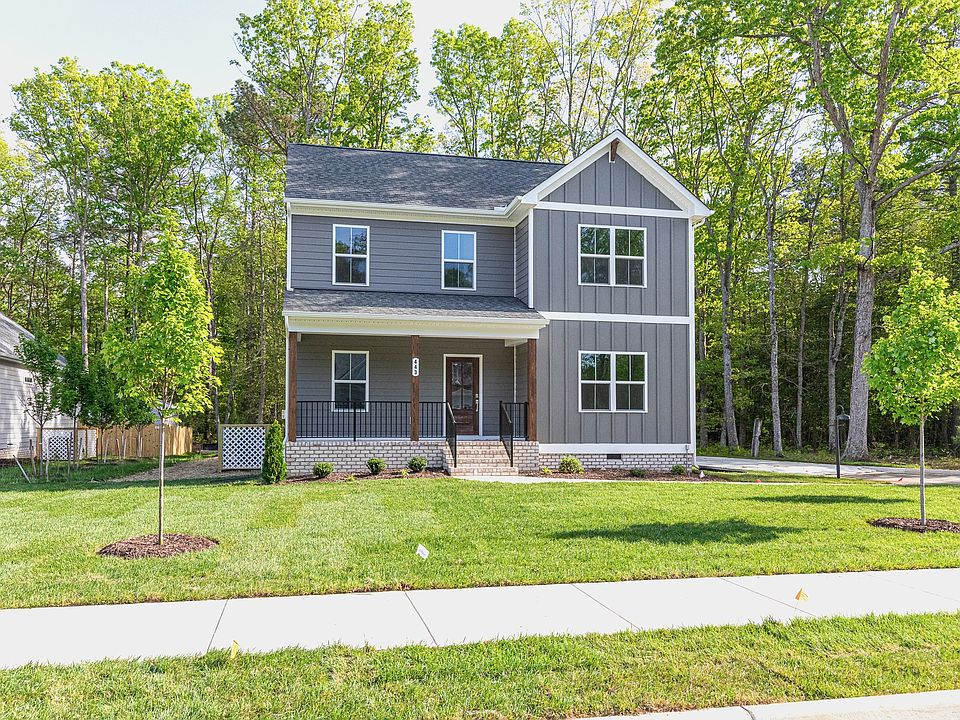 Two-story gray Haley Meadows house with white trim, front porch, green lawn, and trees on a sunny da