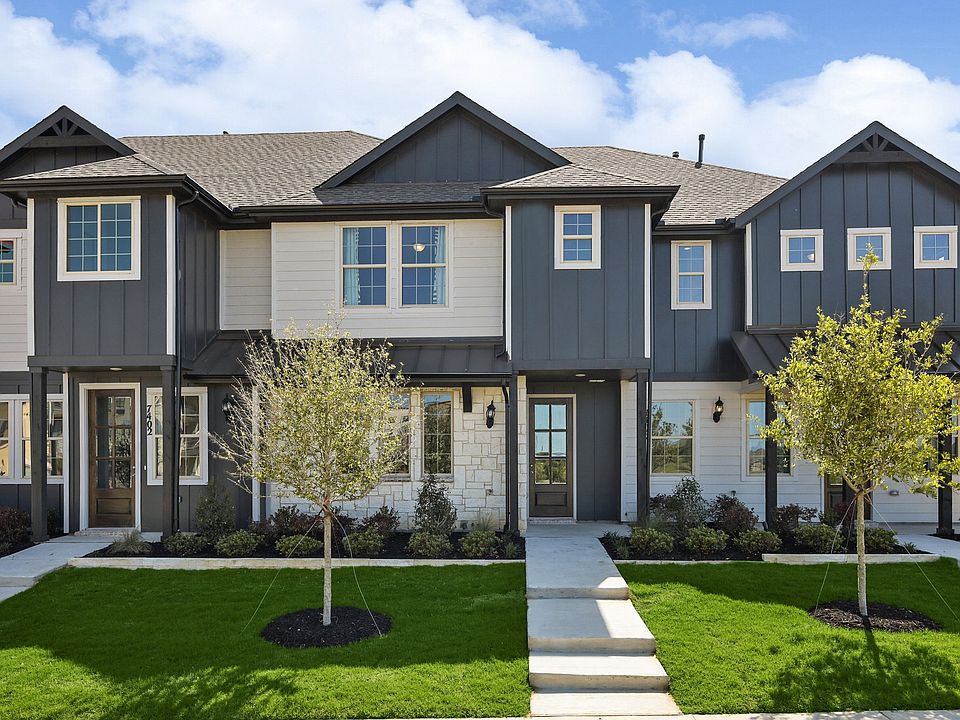 Luxurious townhouse in Hawkes Cove showcases sleek gray siding, elegant white trim, and expansive wi