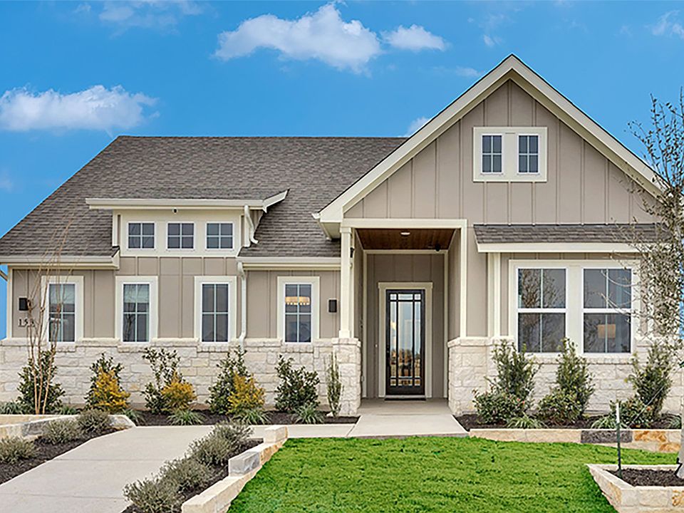 Elegant stone facade, lush landscaping, and gabled roof grace this Spring Creek residence.