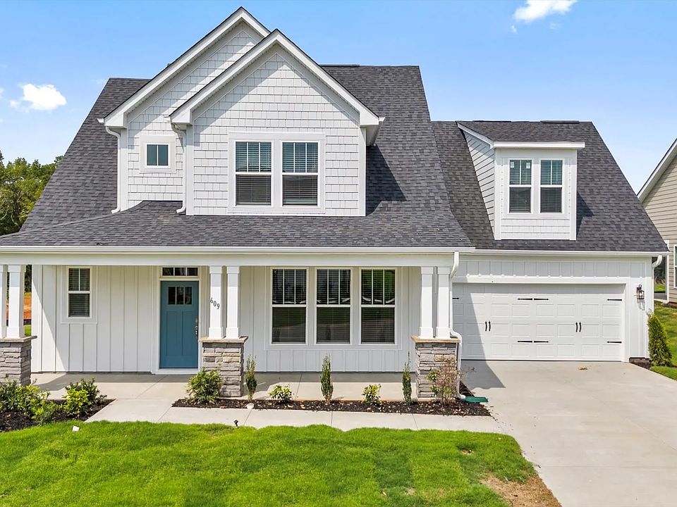 White exterior Sutherland new two story home with stone columns, blue door two car garage at Wells