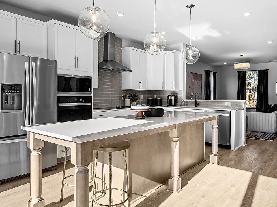 Gourmet kitchen with extended island, vented hood, wall oven microwave, and premium lighting by DRB