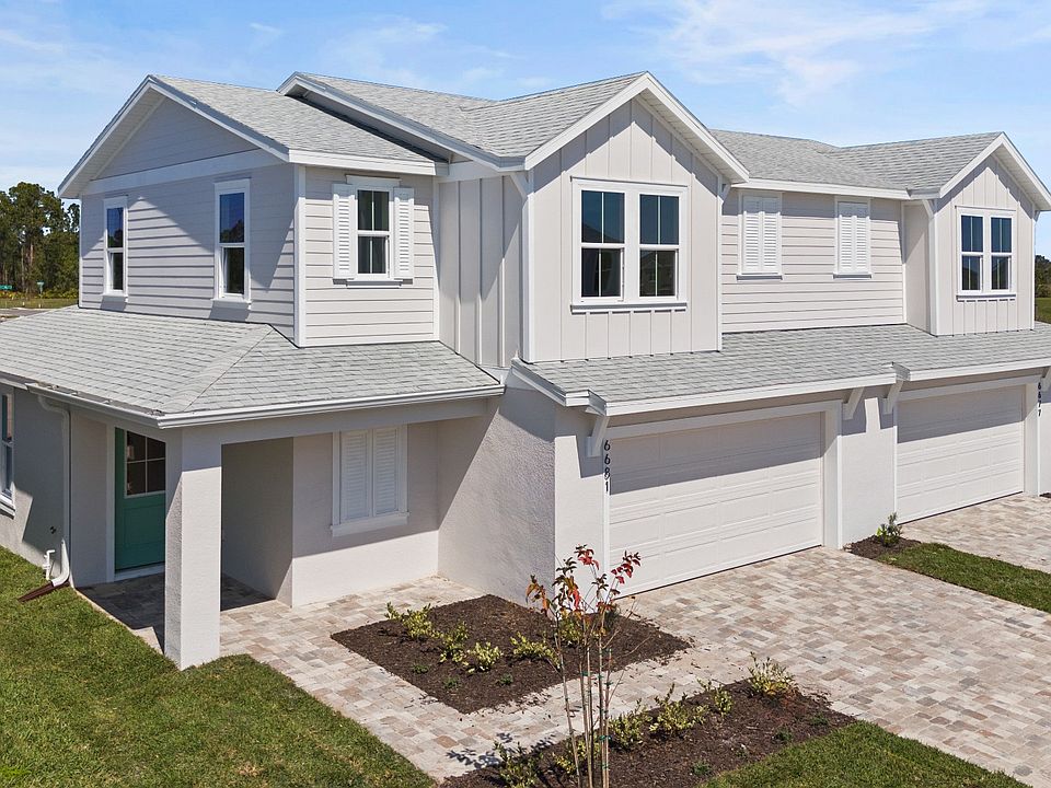 Cyrene at Harmony by DRB Homes features a paver driveway and walkway, enhanced by beautiful landscap