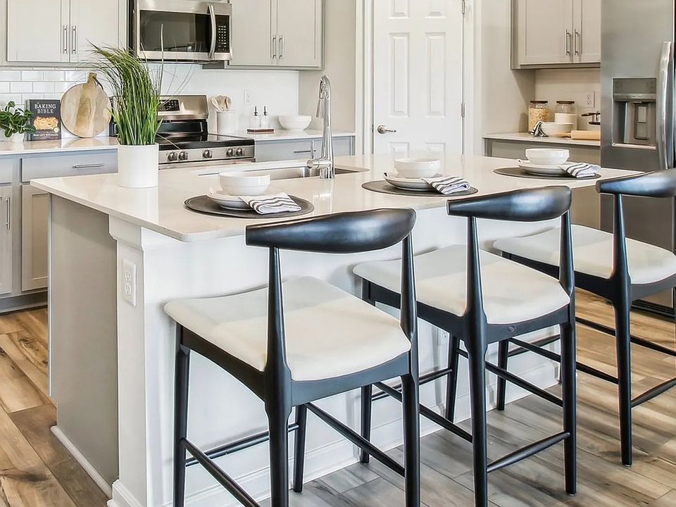 Experience luxury with sleek cabinetry, stainless steel appliances, and elegant island seating in Su