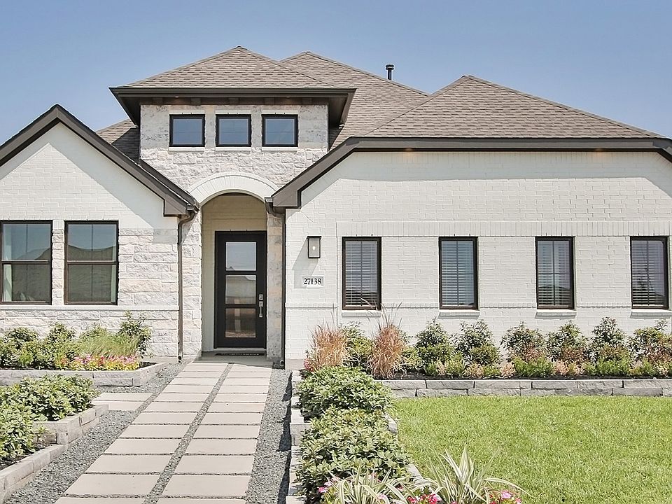 Experience elegance with this Sunterra home, featuring a pristine white brick facade and lush, manic
