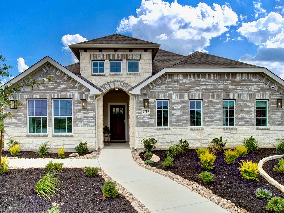 Elegant brick facade with arched entrance and pristine landscaping in Prairie Green community.