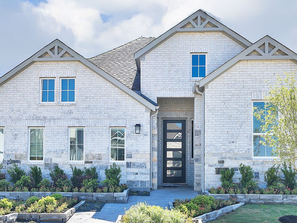 Exquisite white brick facade with gabled roof and geometric door, surrounded by lush landscaping in