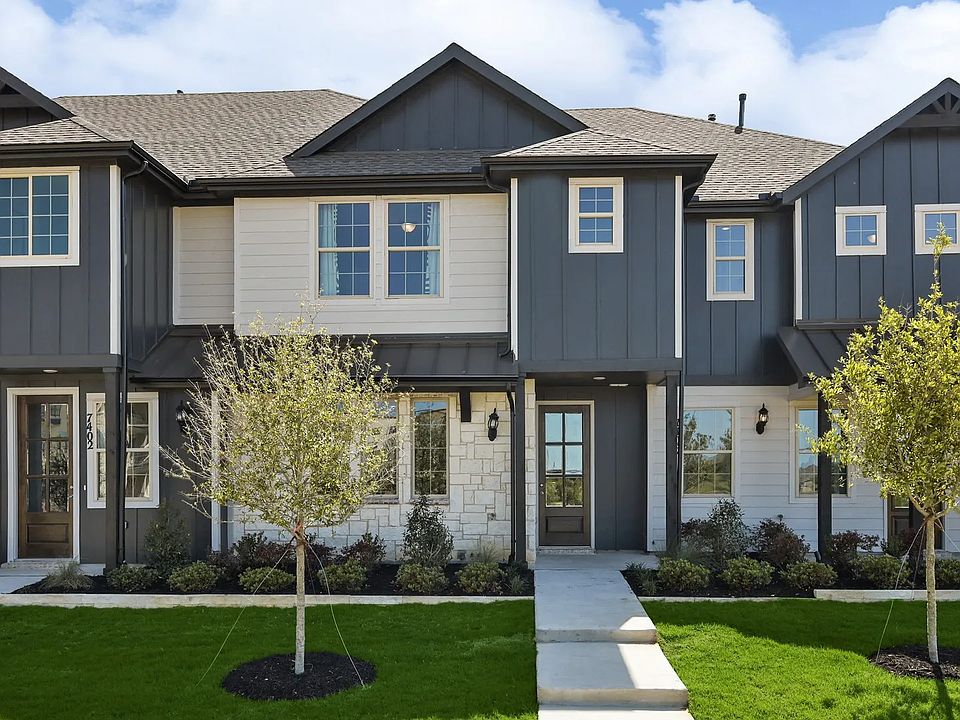 Luxurious townhouse in Hawkes Cove showcases sleek gray siding, elegant white trim, and expansive wi