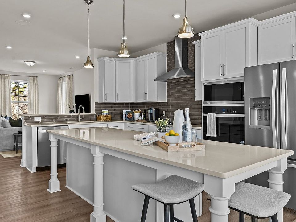Open-Concept Gourmet Kitchen with Extended Island, Wall Oven Microwave, Vented Hood, and Cooktop.