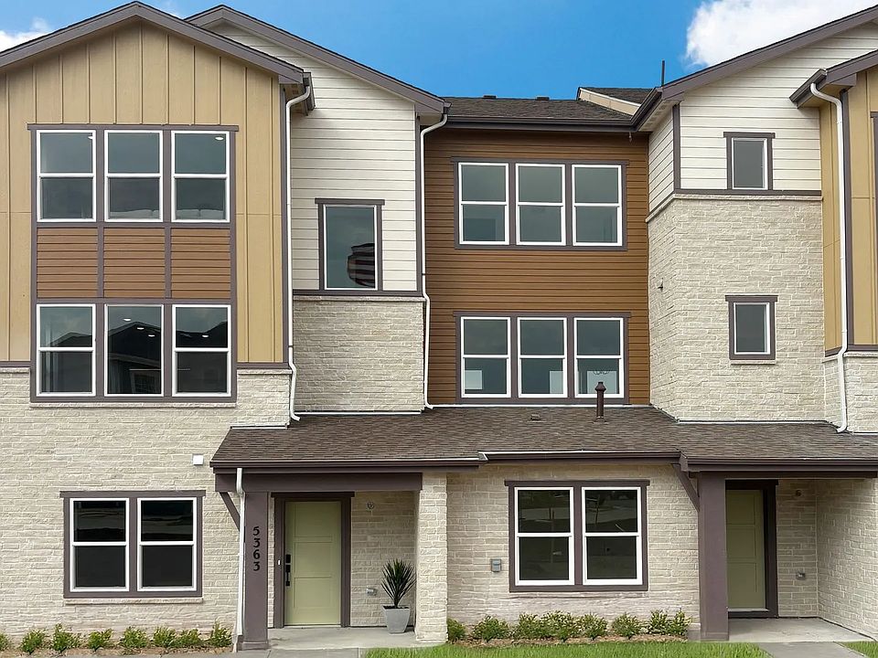 Luxurious Windler Townhomes boast expansive windows and elegant stonework in a serene suburban setti
