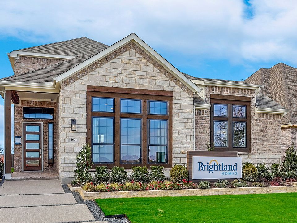 Elegant stone facade with expansive windows in Solterra, Texas. Lush landscaping frames this stunnin