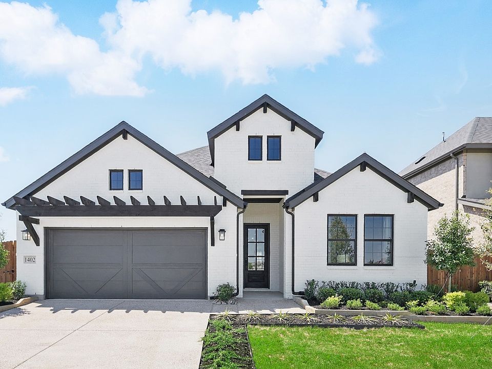 Sophisticated brick facade and gable roof elevate this Aldeana residence. Manicured landscaping adds