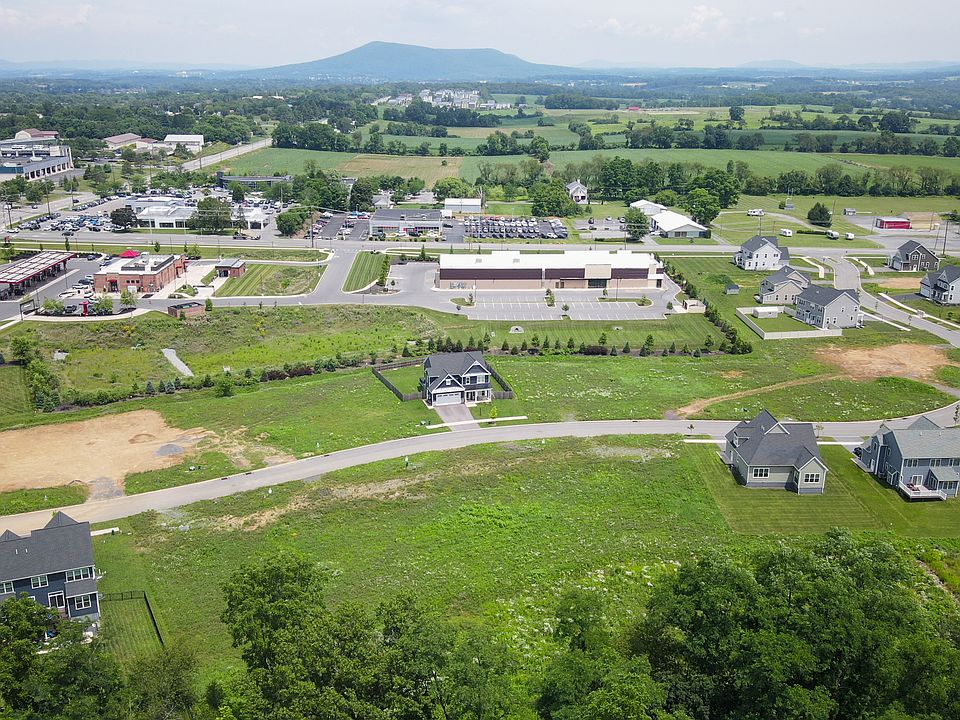 Drone view of Orchard View community near shops and farmland with mountain backdrop